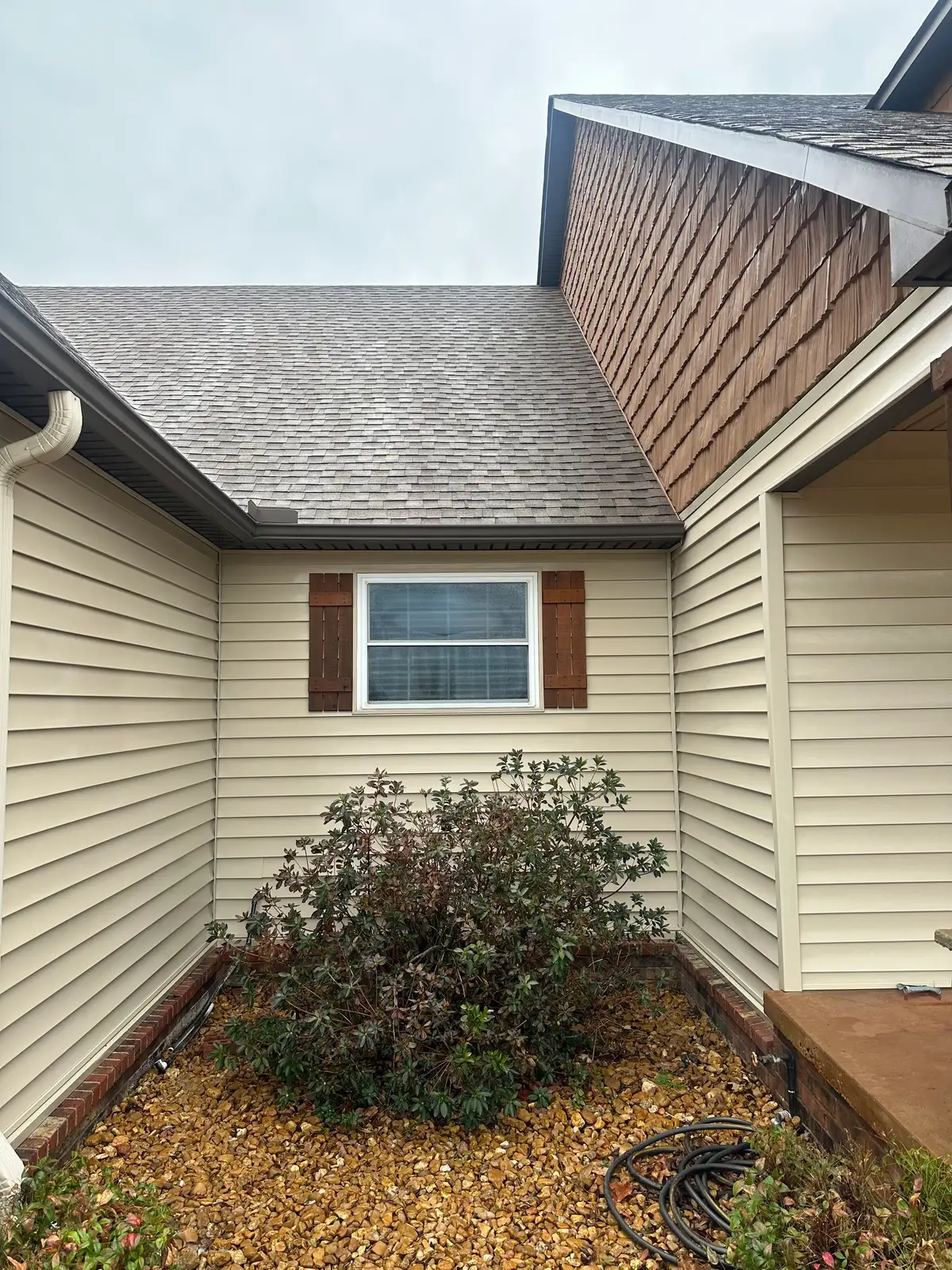 After soft washing: the same side elevation with clean cream vinyl siding, refreshed cedar shakes, and a clear roofline