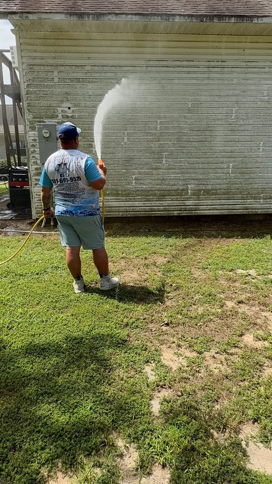 Natural State Soft Wash technician rinsing algae off house siding with a low-pressure soft wash spray in Central Arkansas